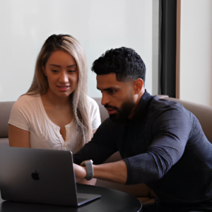 Two colleagues collaborating on a laptop in office lounge.
